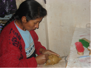 Ceramic Artisan from Quinua Peru putting finishing touches on a piggy bank.